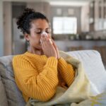 Mulher com sintomas de gripe H1N1 soprando o nariz