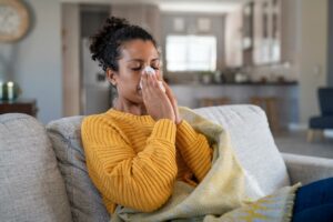 Mulher com sintomas de gripe H1N1 soprando o nariz