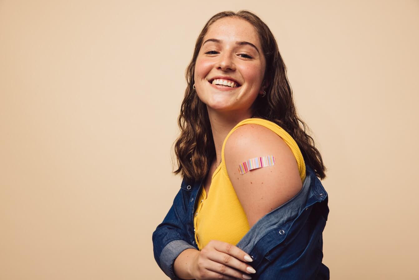 Garota exibindo marca de vacina do HPV